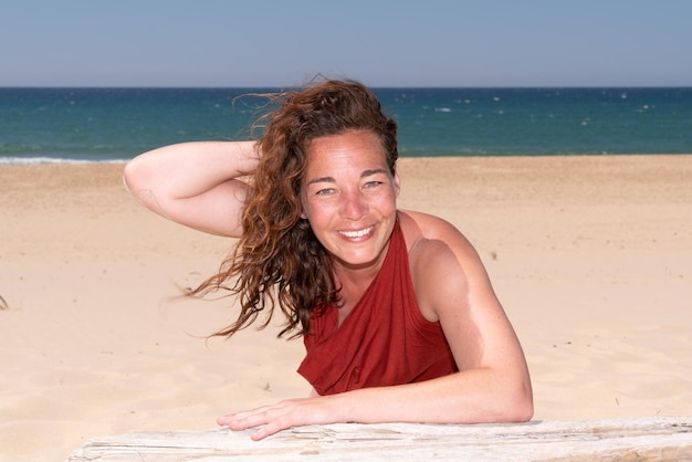 Brunette mature femme bouclée avec le bras tendu debout sur la mer d'été plage