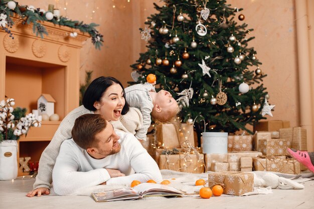 Brunette mère père et petit fils assis près de l'arbre de Noël et jouant