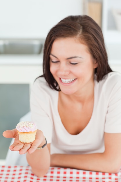 Brunette en riant en regardant un petit gâteau