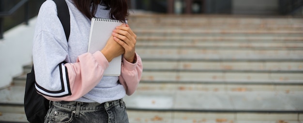 Brunette avec un sac à dos noir et un cahier