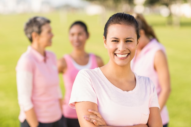 Brunette souriante portant rose pour le cancer du sein devant des amis