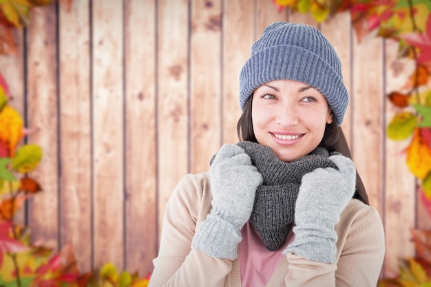 Brunette souriante portant des vêtements chauds contre les feuilles d'automne sur bois