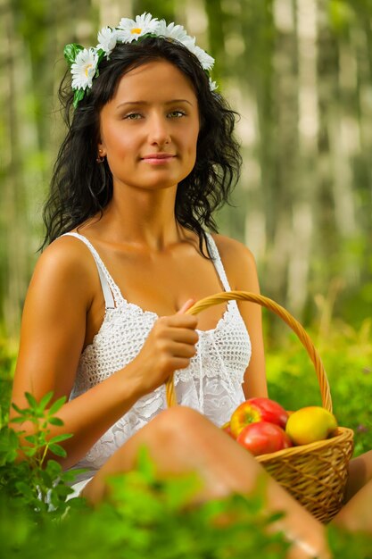 Brunette tenant le panier avec des pommes