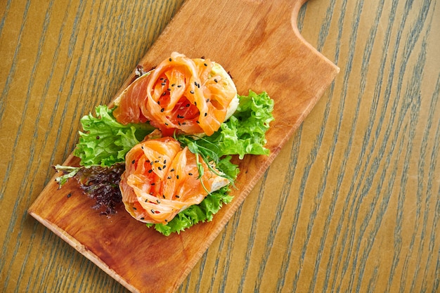 Bruschetta appétissante au saumon et à la laitue sur une planche à découper sur un mur en bois. Gros plan, mise au point sélective