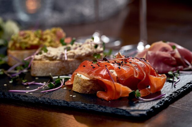 Bruschetta assortie avec jamon, saumon et autres. Apéritifs italiens sur un tableau noir. Fermer