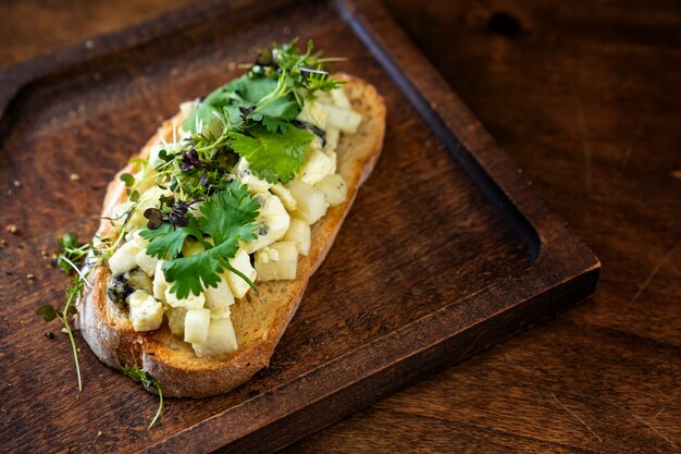 Bruschetta au fromage et légumes verts sur une planche à découper en bois pour les photos