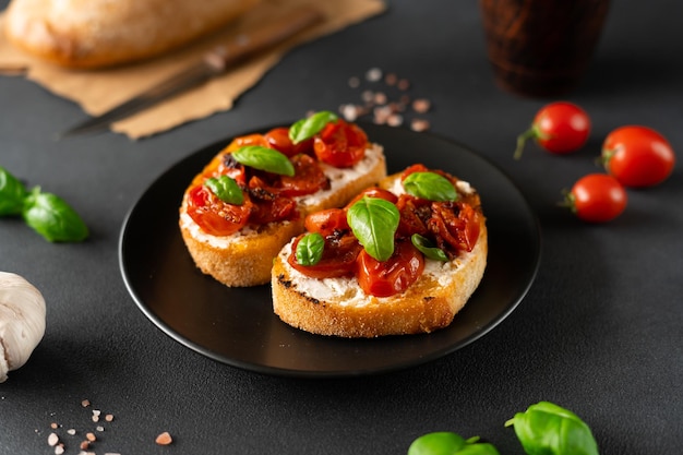 Bruschetta au fromage ricotto et tomates cerises basilic ail sur fond noir