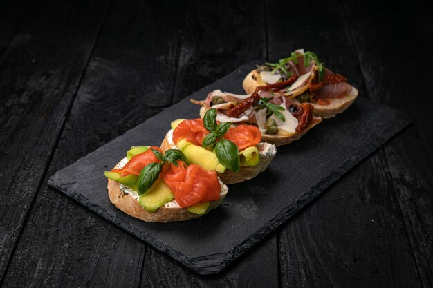 Bruschetta au saumon et viande sur une table en bois foncé