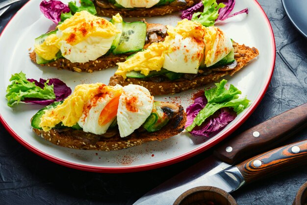 Bruschetta aux oeufs pochés, concombre et compote de champignons.Délicieux petit déjeuner aux oeufs bénédictine