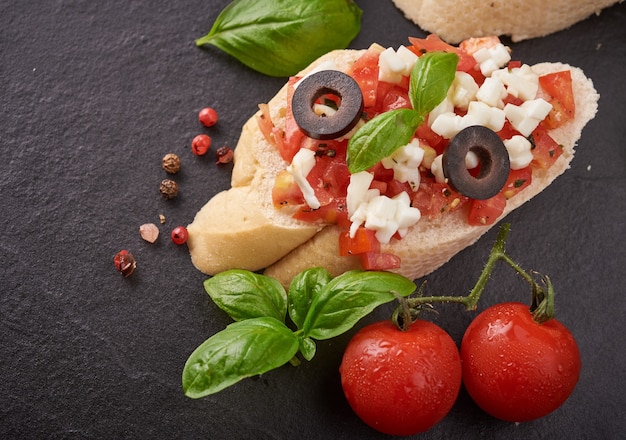 Bruschetta aux tomates, fromage mozzarella et basilic sur une planche à découper. Apéritif ou collation italienne traditionnelle, antipasti. Bruschetta de salade caprese. Vue de dessus avec espace de copie. Mise à plat.