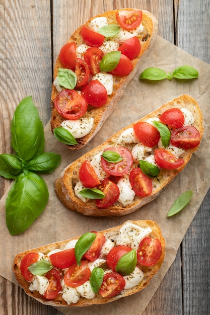 Bruschetta aux tomates, fromage mozzarella et basilic sur une vieille table rustique