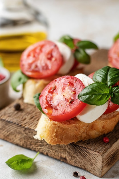 Bruschetta aux tomates mozzarella et basilic sur planche de bois rustique gros plan avec ingrédients