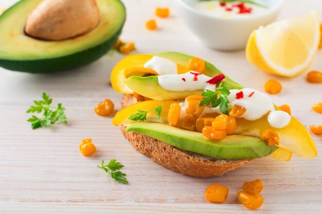 Bruschetta à l'avocat, poivron jaune, grains de maïs, persil et piment