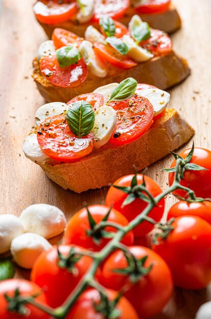 Photo bruschetta caprese feuilles de basilic frais tomates aromatiques mûres et mozzarella italienne sur bruschetta arrosée d'huile d'olive et saupoudrée de poivre et d'herbes