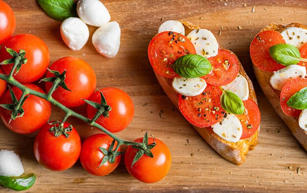 Photo bruschetta caprese feuilles de basilic frais tomates aromatiques mûres et mozzarella italienne sur bruschetta arrosée d'huile d'olive et saupoudrée de poivre et d'herbes