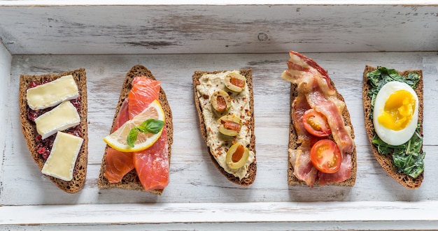 Bruschetta avec différentes garnitures sur le plateau en bois