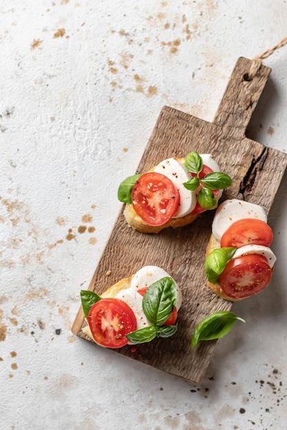 Bruschetta italienne aux tomates mozzarella et basilic sur planche de bois rustique vue de dessus espace texte