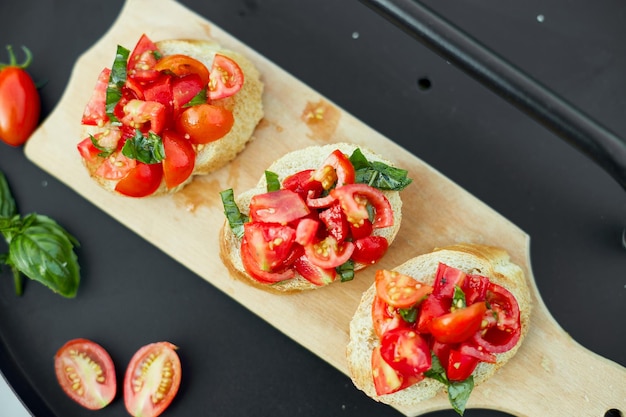 Bruschetta italienne aux tomates rouges fraîches et aux herbes de basilic sur une planche de bois en plein air