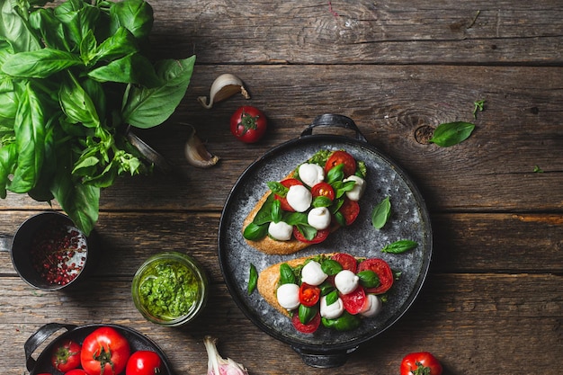 Bruschetta avec mozzarella, tomates, basilic et pesto dans une assiette Bruschetta Caprese