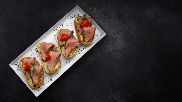 Bruschetta avec sauce à la viande et tomates sur fond sombre