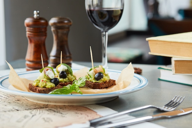 Bruschetta sur une table en bois dans une assiette blanche et un verre de vin rouge