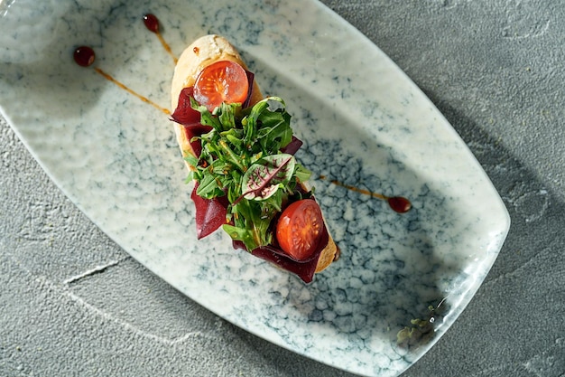 Bruschetta végétarienne aux betteraves tomates et roquette dans une assiette sur un fond de béton