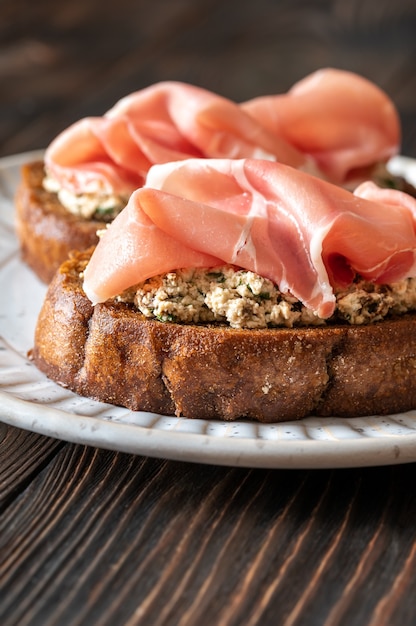 Bruschettas au fromage à la crème, tomates séchées au soleil et prosciutto dans l'assiette