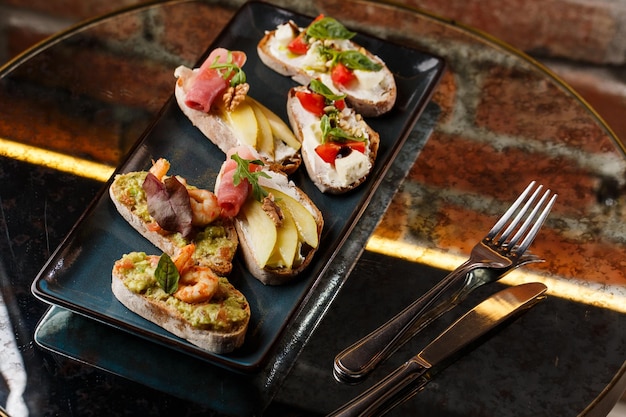 Photo bruschettas aux légumes commencez les plats avec des tomates cerises, du fromage à la crème d'avocat et des crevettes composition alimentaire savoureux repas italien