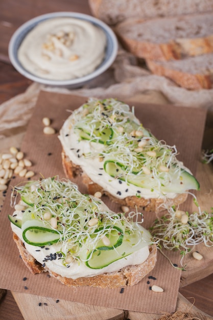 Bruschettas végétariennes saines avec pain, micro-légumes verts, houmous, concombres et pignons de pin