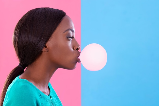 Bubblicious Prise de vue en studio d'une jolie jeune femme soufflant une bulle de gomme sur un fond coloré