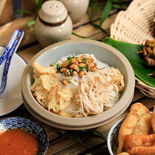 Bubur Ayam ou bouillie de riz indonésienne avec poulet râpé. Servi avec Kerukpuk (craquelins), sauce soja, fèves de soja frites et sambal