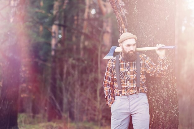 Un bûcheron barbu avec une grande hache examine l'arbre avant de l'abattre