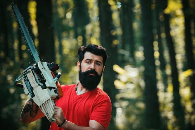 Bûcheron dans les bois avec une hache de tronçonneuse bûcheron professionnel tenant une tronçonneuse dans la forêt woo