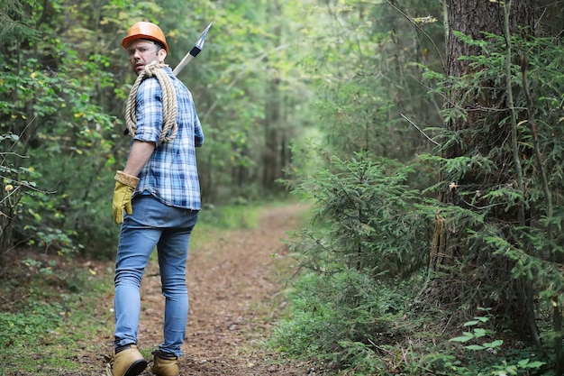 Bûcheron mâle dans la forêt. Un bûcheron professionnel inspecte les arbres pour l'abattage.