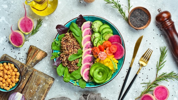 Buddha bowl : Quinoa, radis pastèque, concombre, tomate et épinards. Délicieux concept de nutrition équilibrée sur fond de pierre.