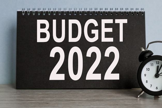 BUDGET 2022, réveil, bloc-notes NOIR avec texte, sur fond bleu, Temps qui s'enfuit.