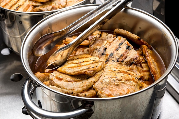 Buffet de restaurant mis en place avec des cuiseurs à riz, des haricots, du poulet et de la viande.