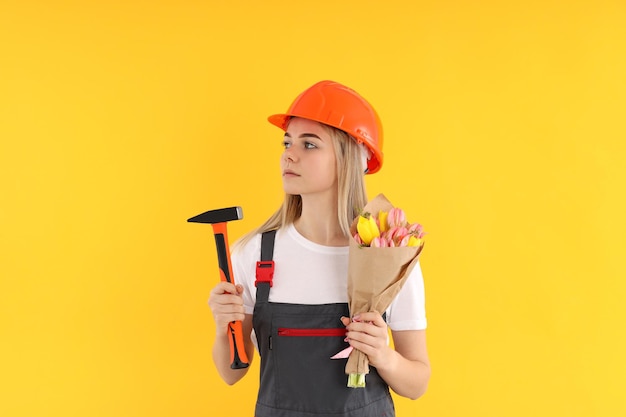 Builder fille avec bouquet de fleurs sur fond jaune