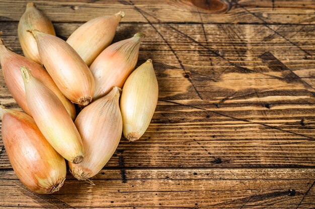 Bulbes d'oignons échalotes frais sur la table de la cuisine. Fond en bois. Vue de dessus. Espace de copie.