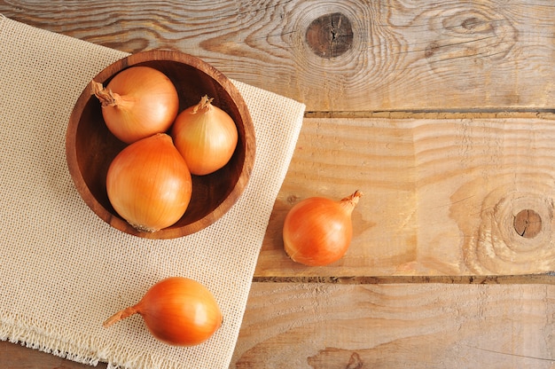 Bulbes d'oignons entiers dans une assiette en bois