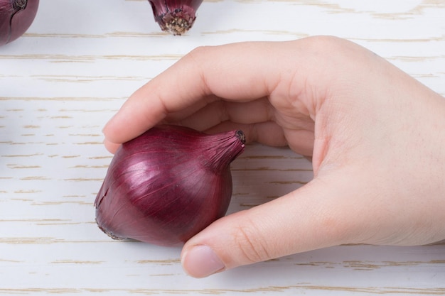 Bulbes d'oignons rouges entiers en brun sur fond de bois
