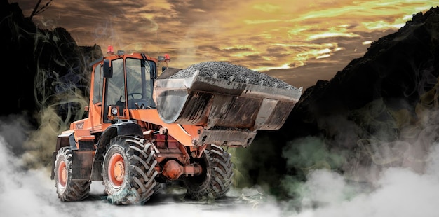 Bulldozer ou chargeur sur un chantier de construction travaillant dans la fumée ou le brouillard Puissant chargeur sur pneus ou bulldozer avec un grand godet Travaux de construction compliqués Matériel de construction pour les travaux de terrassement