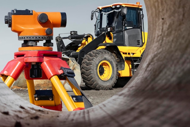 Un bulldozer ou un chargeur planifie le sol sur un chantier de construction Vue depuis un gros tuyau Gros plan sur un équipement de terrassement Équipement géodésique un niveleur pour un travail précis Construction moderne