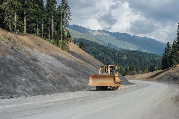 Bulldozer sur chenilles roulant sur un chemin de terre dans les montagnes