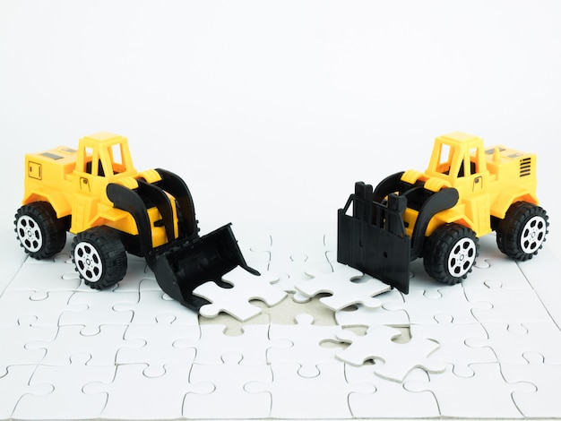 Bulldozer de jouet et chariot élévateur avec Jigsaw puzzle sur fond blanc
