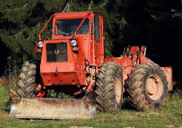 Photo un bulldozer rouge sur un champ herbeux