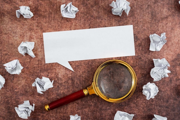 Photo bulle de dialogue faite de feuille avec loupe entourée de papiers froissés sur fond de bois il montre différentes pensées et analyse des stratégies