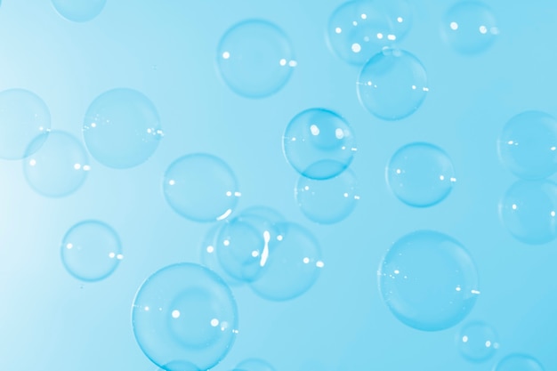 Bulles de savon transparentes claires flottant sur fond bleu.