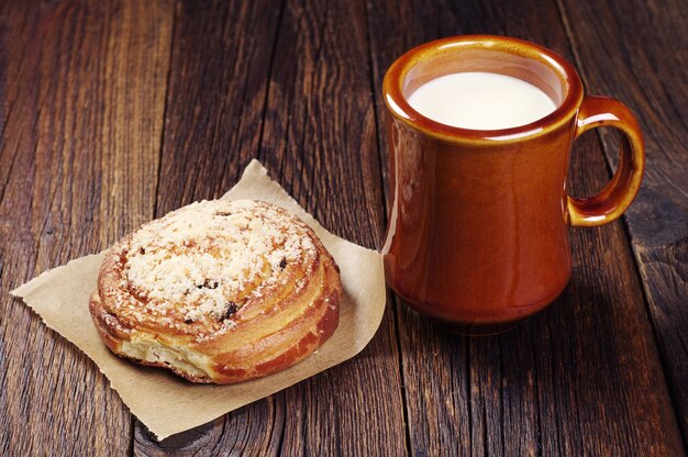 Bun et tasse de lait sur la vieille table en bois