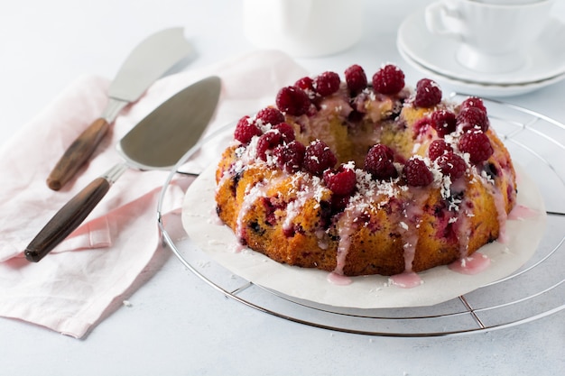 Bundt-cake au citron avec des framboises sur une lumière.